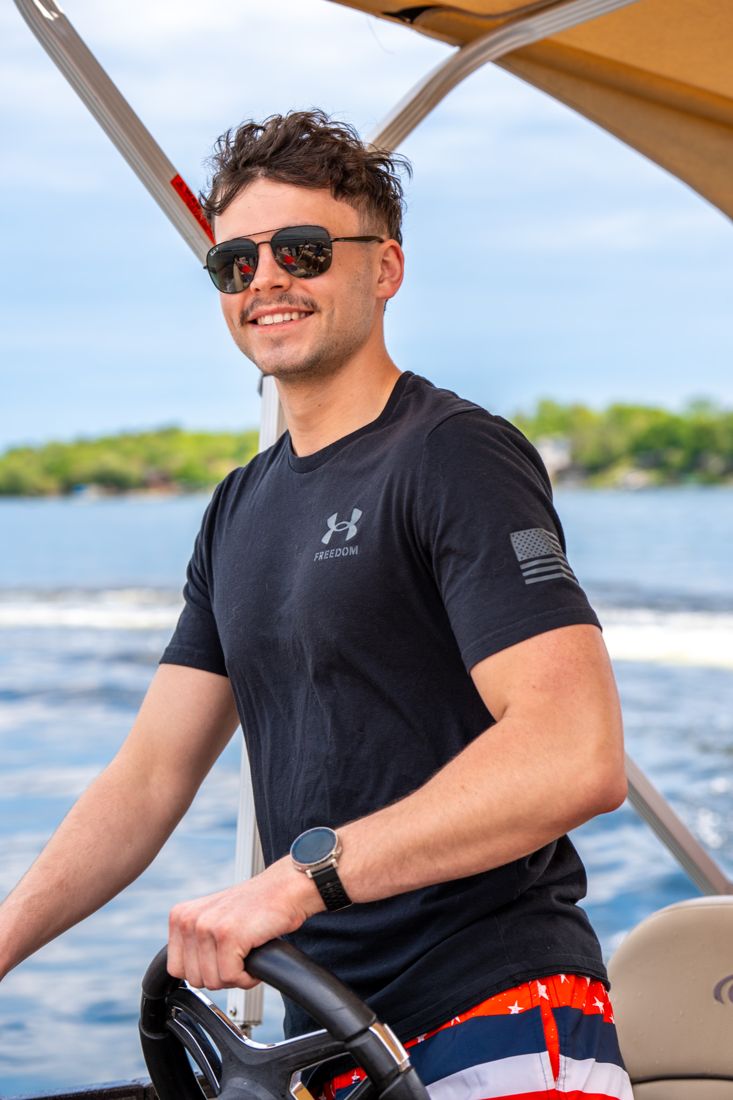 A smiling driver at the helm of a pontoon on a sunny day